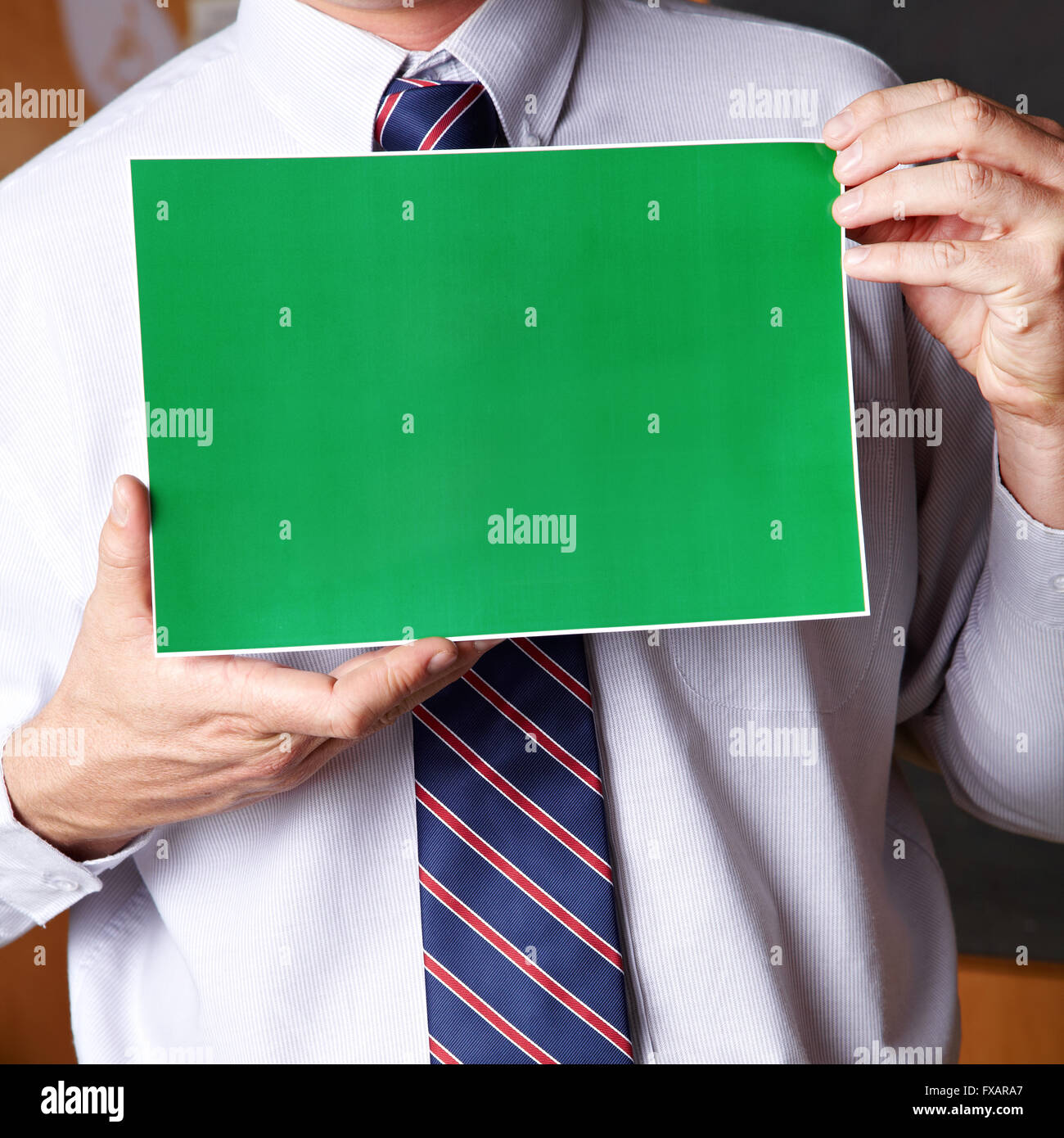 Manager holding empty green sign in front of his chest Stock Photo