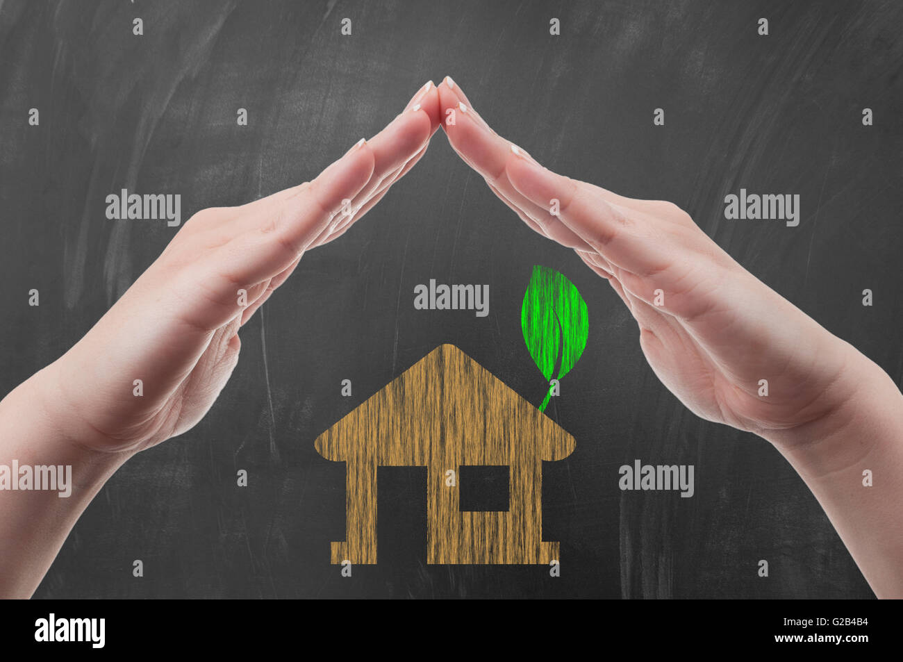 Hands protecting green energy house concept draw on blackboard or school chalkboard Stock Photo