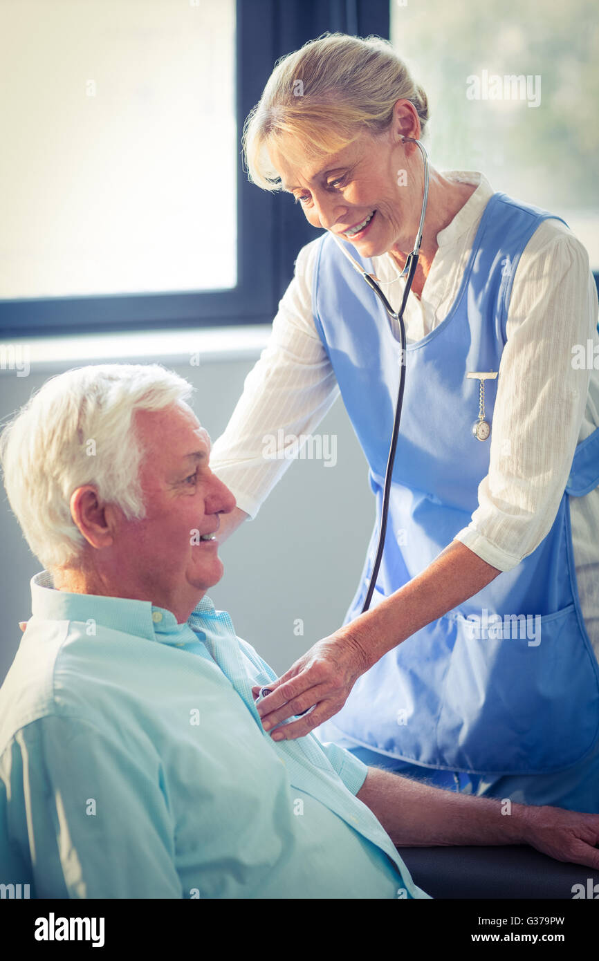 Female doctor checking heartbeat of senior man Stock Photo