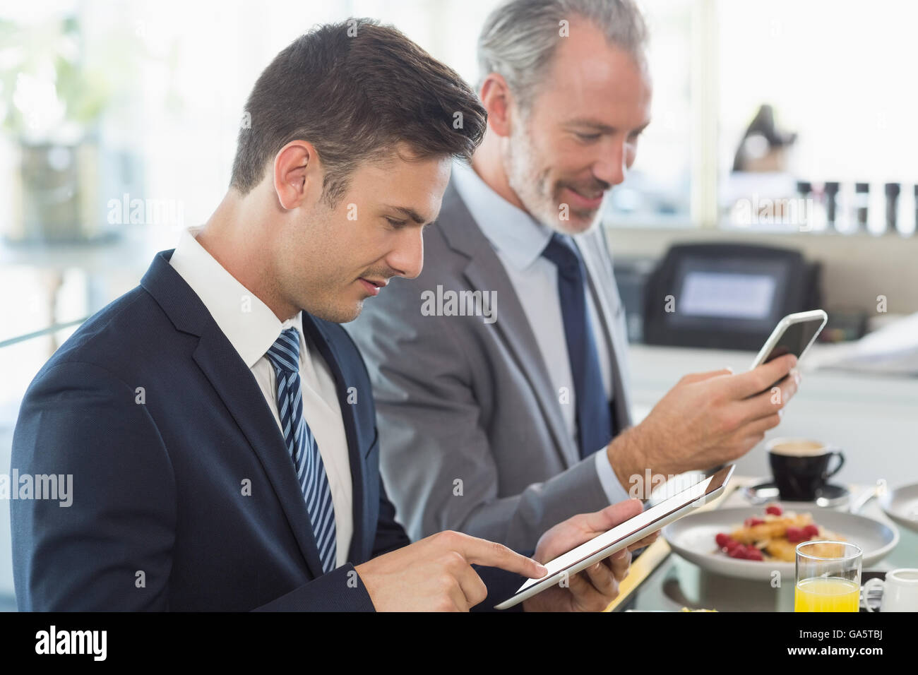 Two businessmen using digital tablet and mobile phone Stock Photo