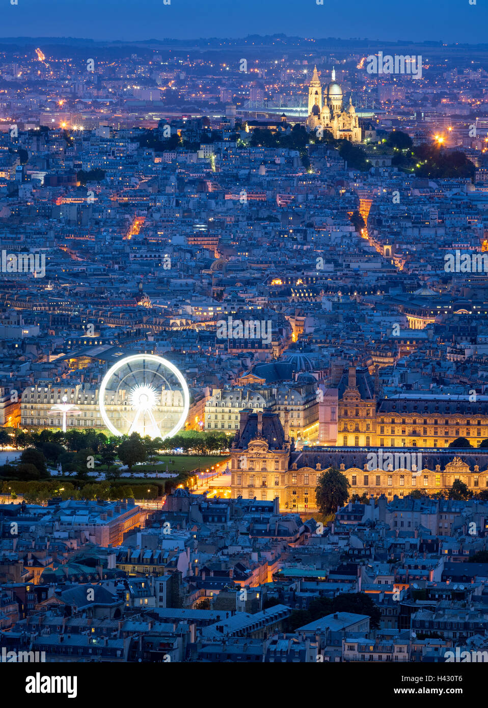 Aerial view of Paris rooftops at dusk, including The Louvre, and Sacre Coeur in Montmartre. Blue hour in the City of Light Stock Photo