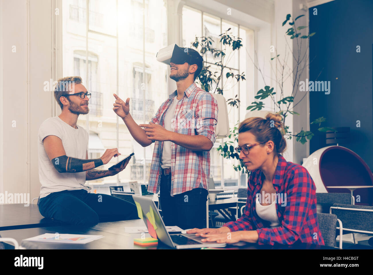 Entrepreneurs testing virtual reality technology with colleague in office. Stock Photo