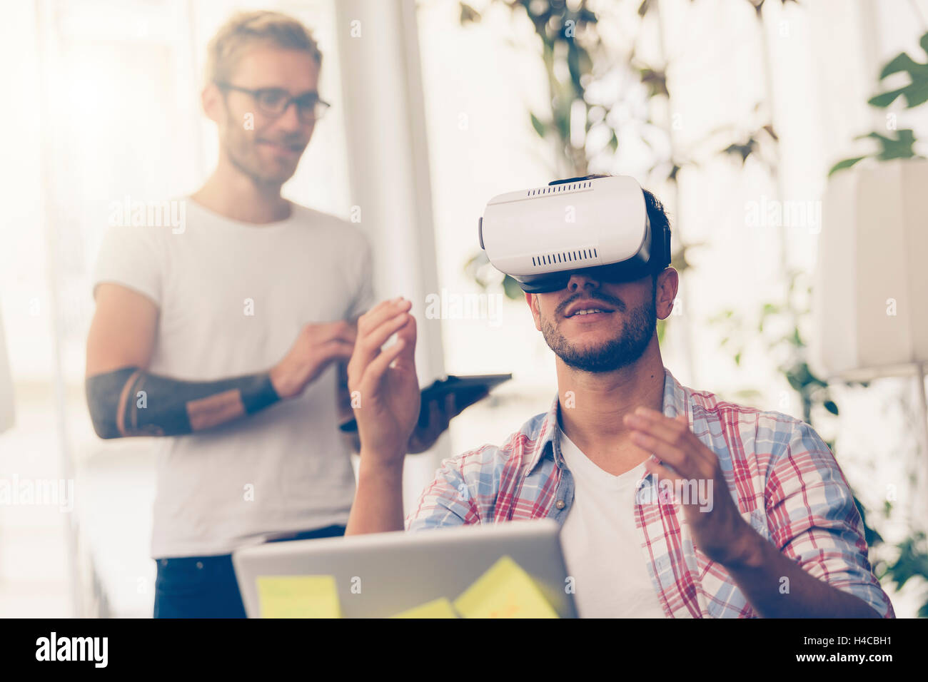 Entrepreneurs testing virtual reality technology with colleague in office. Stock Photo