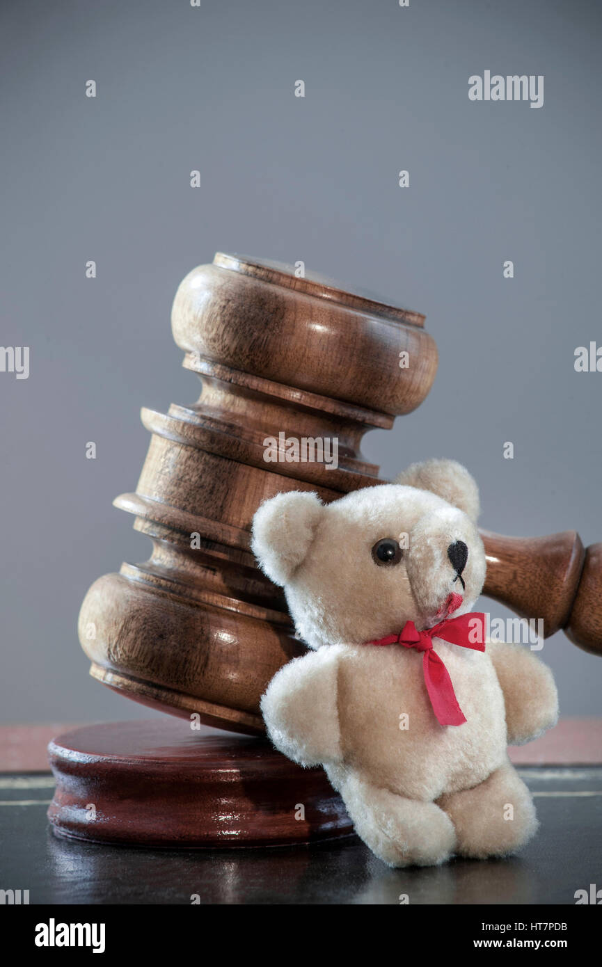 Judges Gavel child rights custody divorce abuse trust legal concept on desk with child's small Teddy Bear leaning against in law court environment Stock Photo