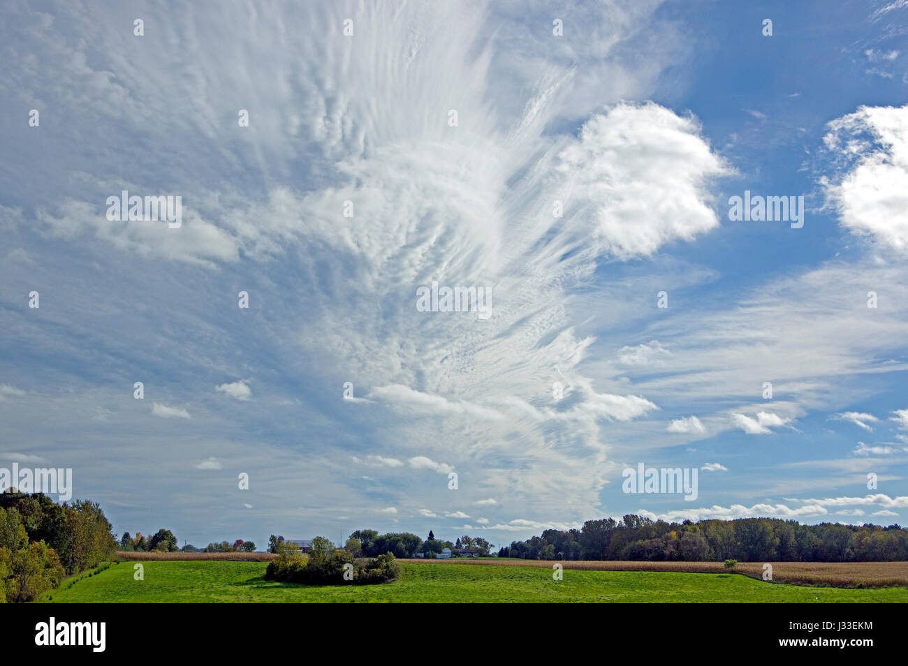 Windswept mare’s tails and mackerel scales cirrus and altocumulus clouds over Wisconsin farmland Stock Photo