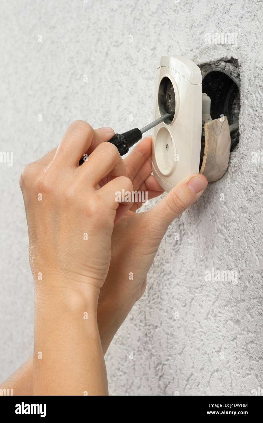 hands of electrician dismantling broken wall electric socket Stock Photo