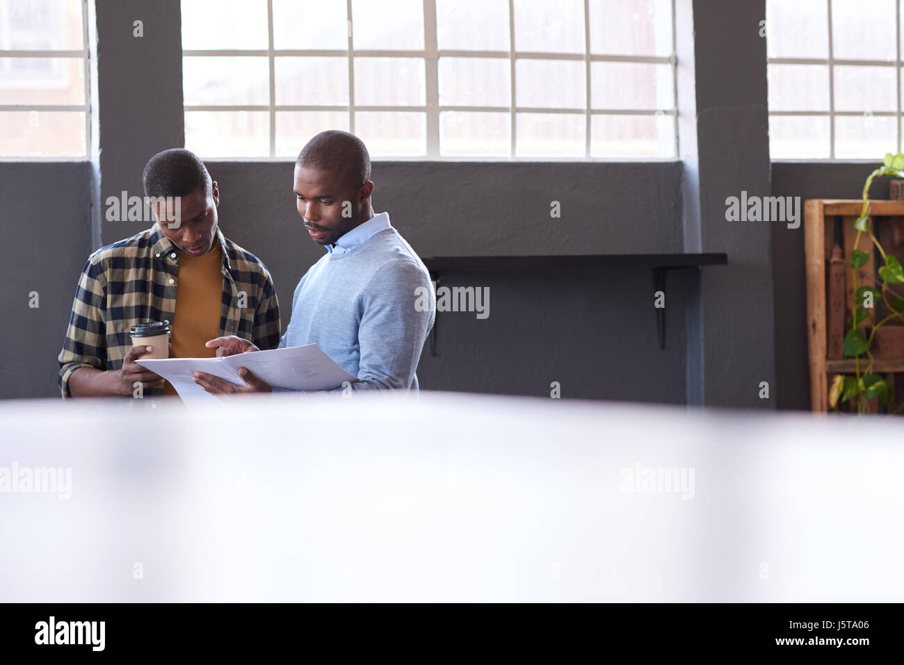 Young African businessmen discussing paperwork together in an office Stock Photo