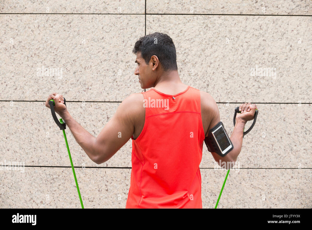 Portrait of an athletic Indian man using stretch bands outdoors in urban setting. Stock Photo