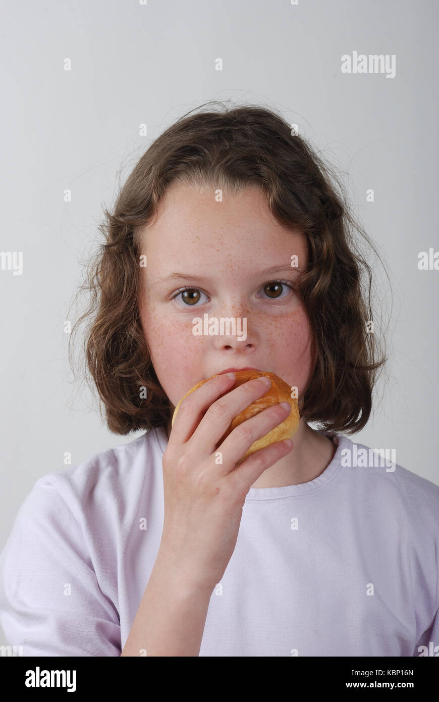 A young girl eating a bun Stock Photo - Alamy