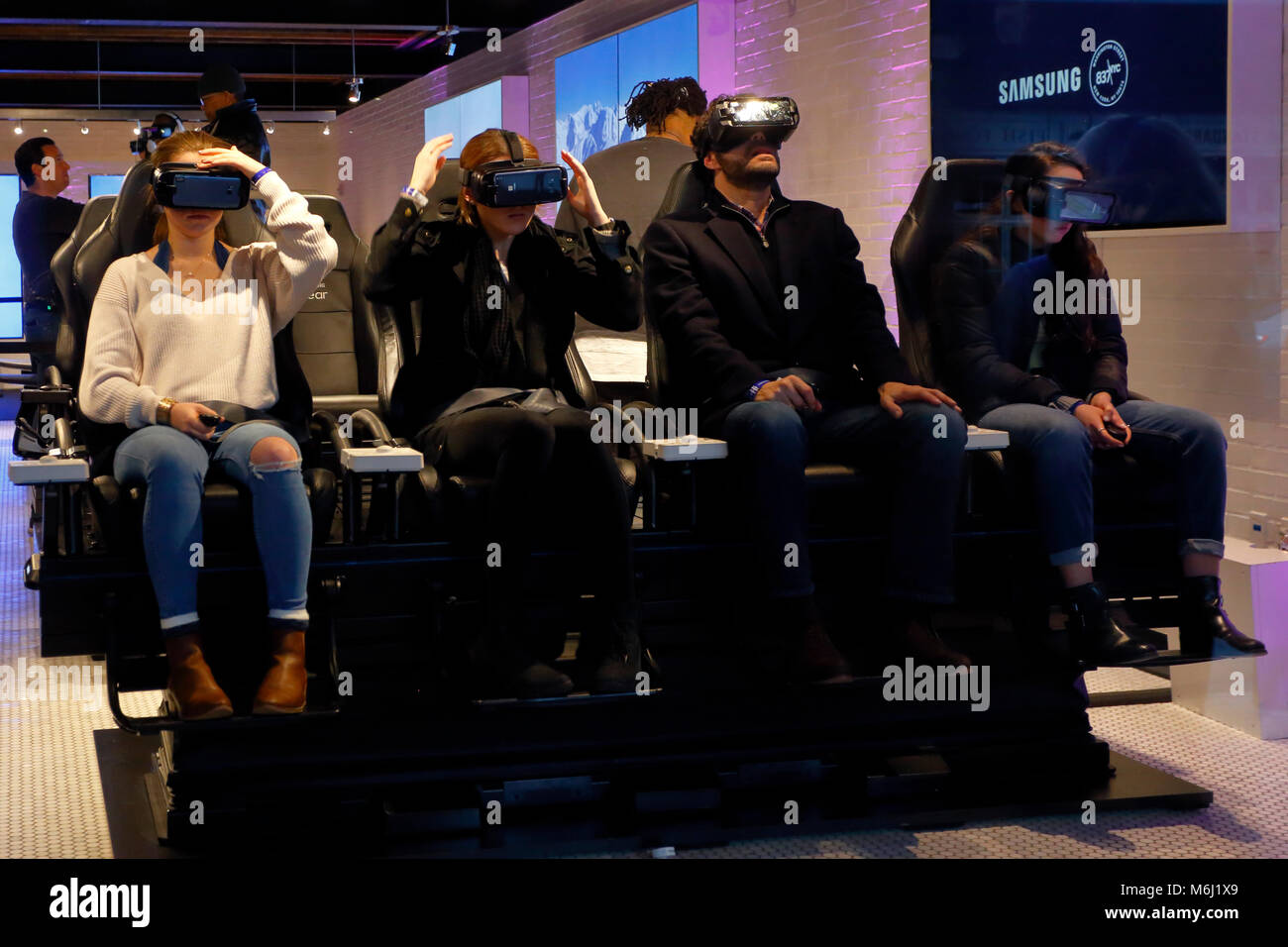 People wearing virtual reality goggles at a technology store; the vr headsets turn movie watching into a personal immersive experience. Stock Photo