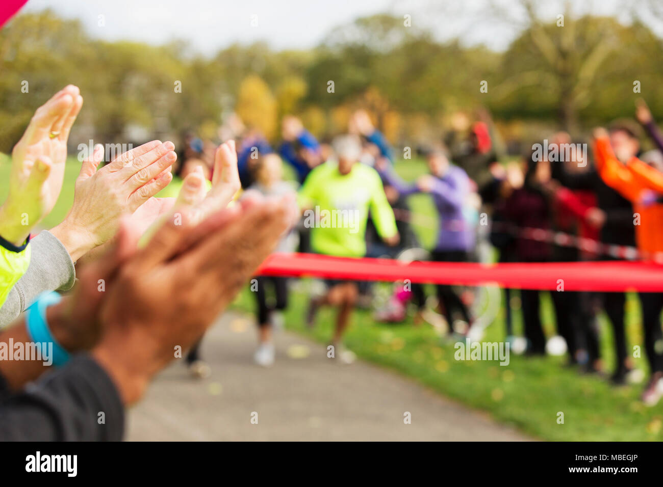 Spectators clapping for runners nearing finish line at charity event Stock Photo