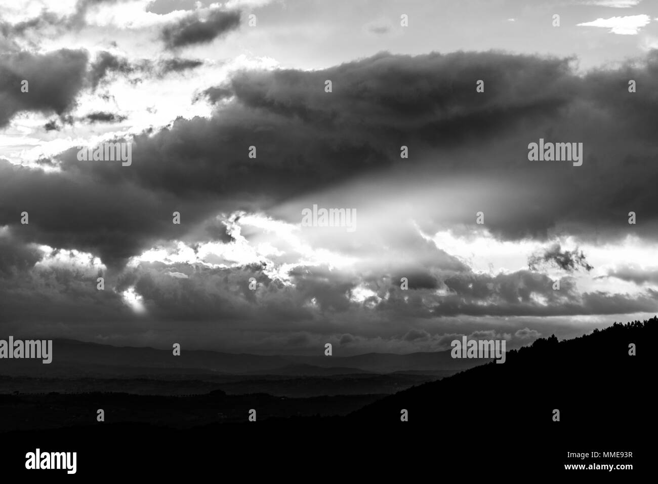 Sunset over a valley, with sun rays coming out through some clouds Stock Photo