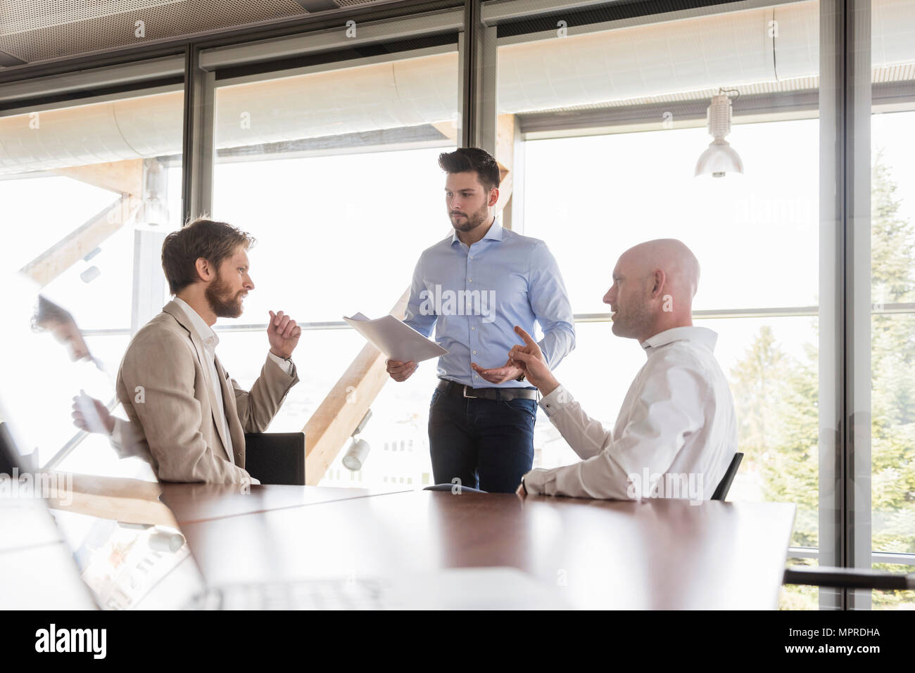 Three businessmen discussing in conference room Stock Photo