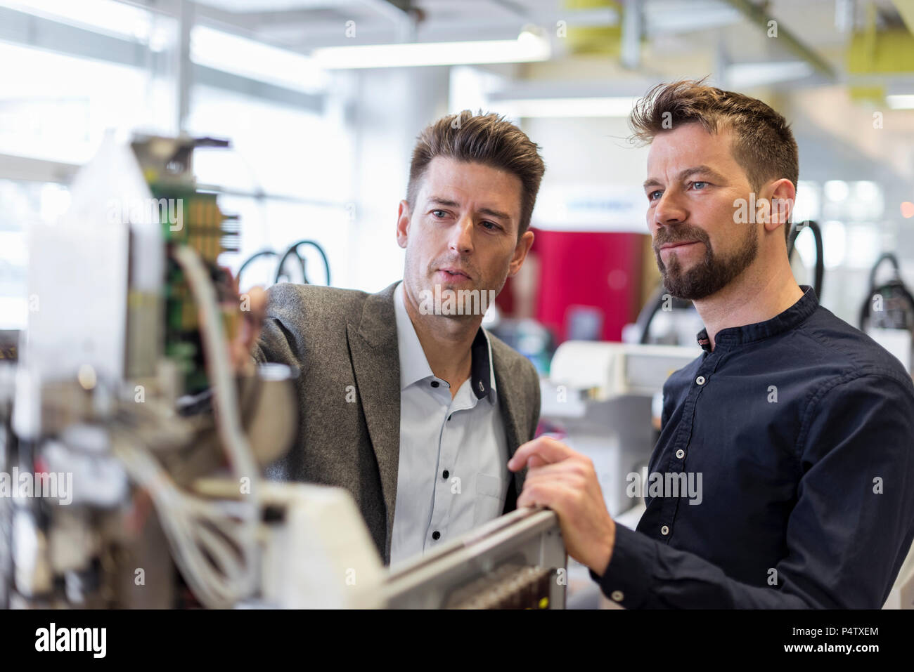 Two businessmen examining device in factory Stock Photo