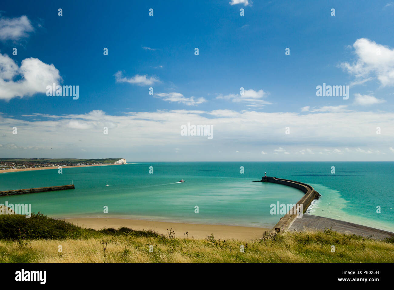 Fishing boat heading out to sea from Newhaven harbour, East Sussex,  England from Fort Hill with the town of Seaford in the distance. Stock Photo