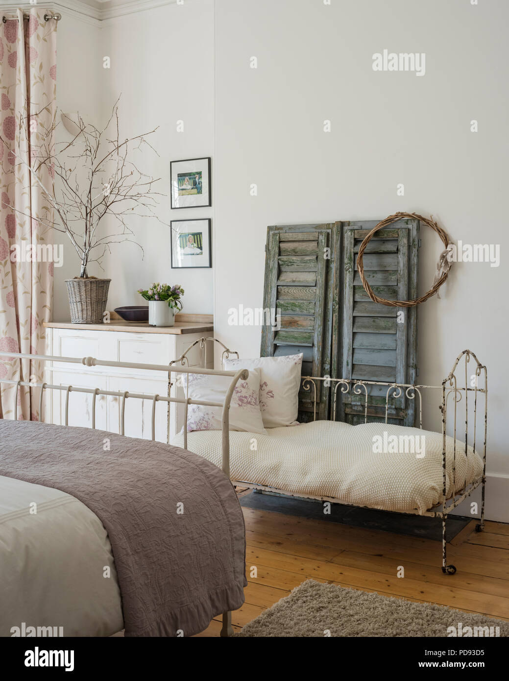 Beautiful antique shutters and iron framed day bed in guest bedroom Stock Photo