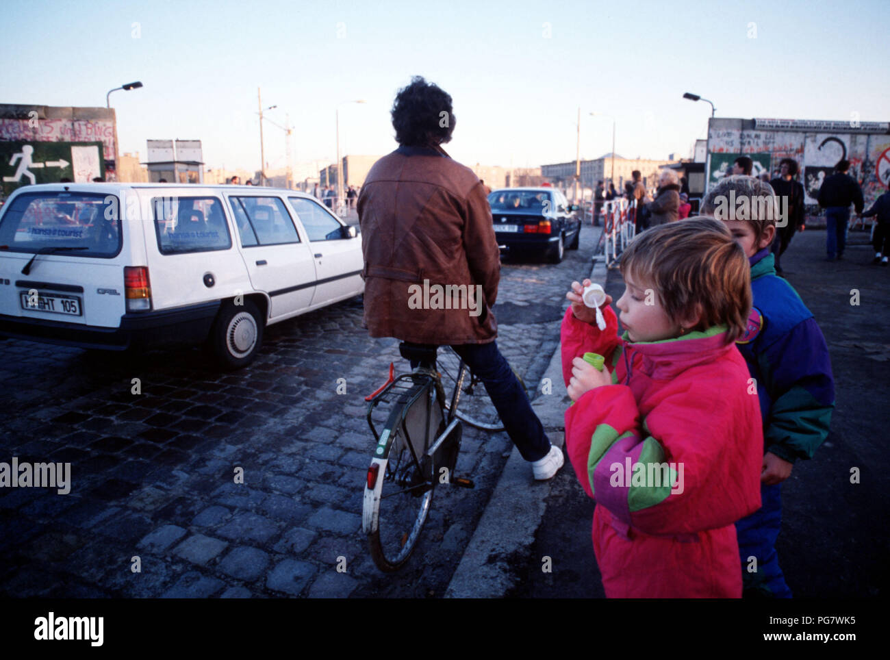 A child blows bubbles at the passing traffic as cars move between East and West Berlin at Potsdamer Platz. Stock Photo