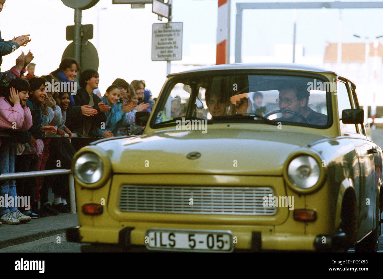 West German children applaud as an East German couple drive through Checkpoint Charlie and take advantage of relaxed travel restrictions to visit West Germany. Stock Photo