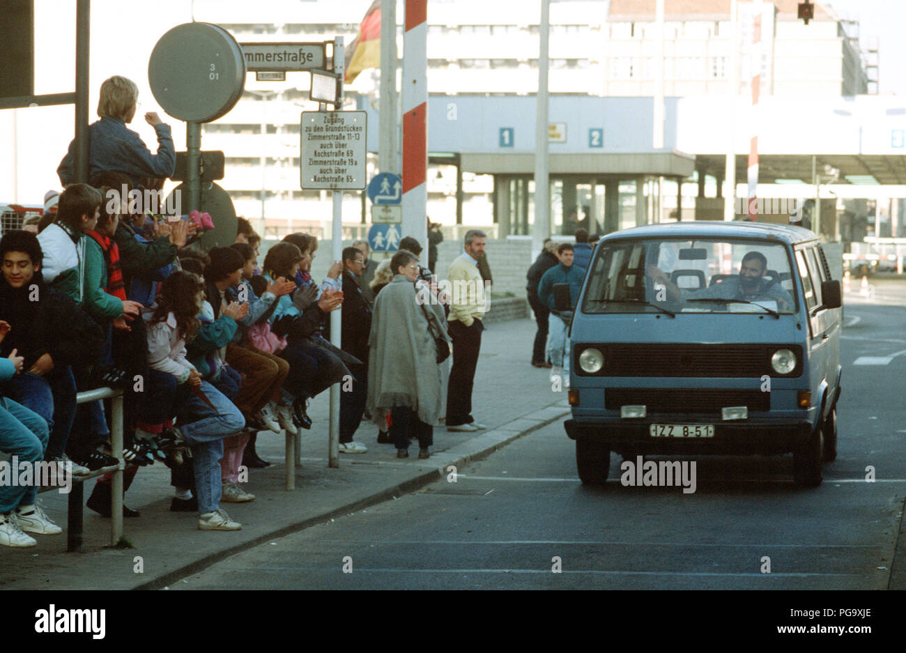 West German children applaud as an East German man drives through Checkpoint Charlie and takes advantage of relaxed travel restrictions to visit West Germany. Stock Photo