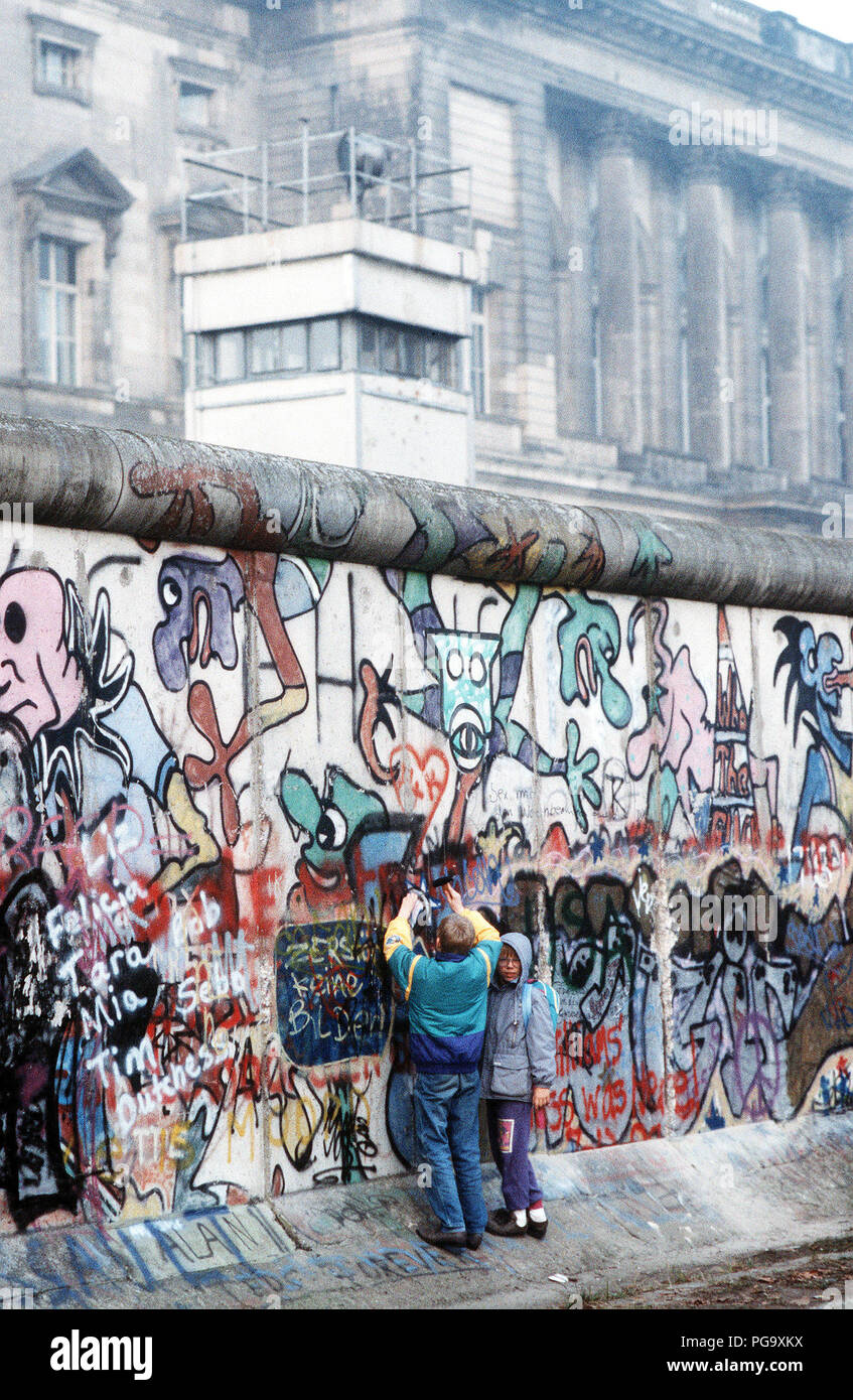 West German children attempt to chip off a piece of the Berlin Wall as a souvenir.  A portion of the Wall has already been demolished at Potsdamer Platz. Stock Photo