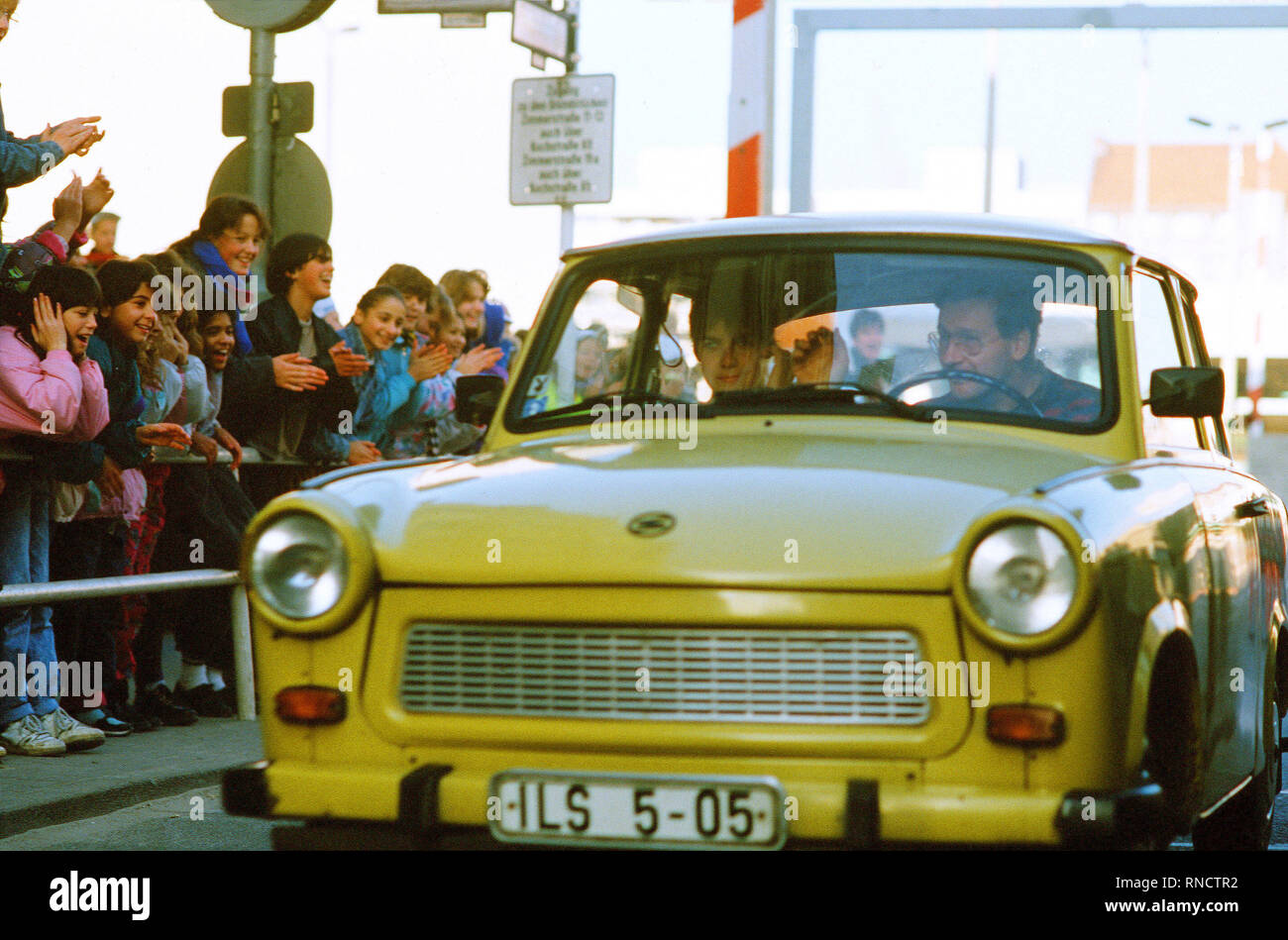 West German children applaud as an East German couple drive through Checkpoint Charlie and take advantage of relaxed travel restrictions to visit West Germany. Stock Photo