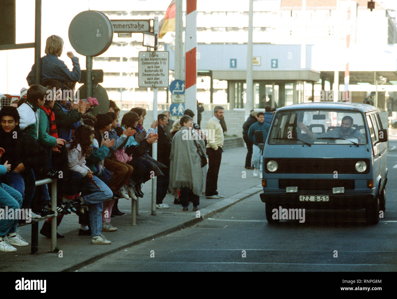 West German children applaud as an East German man drives through Checkpoint Charlie and takes advantage of relaxed travel restrictions to visit West Germany. Stock Photo