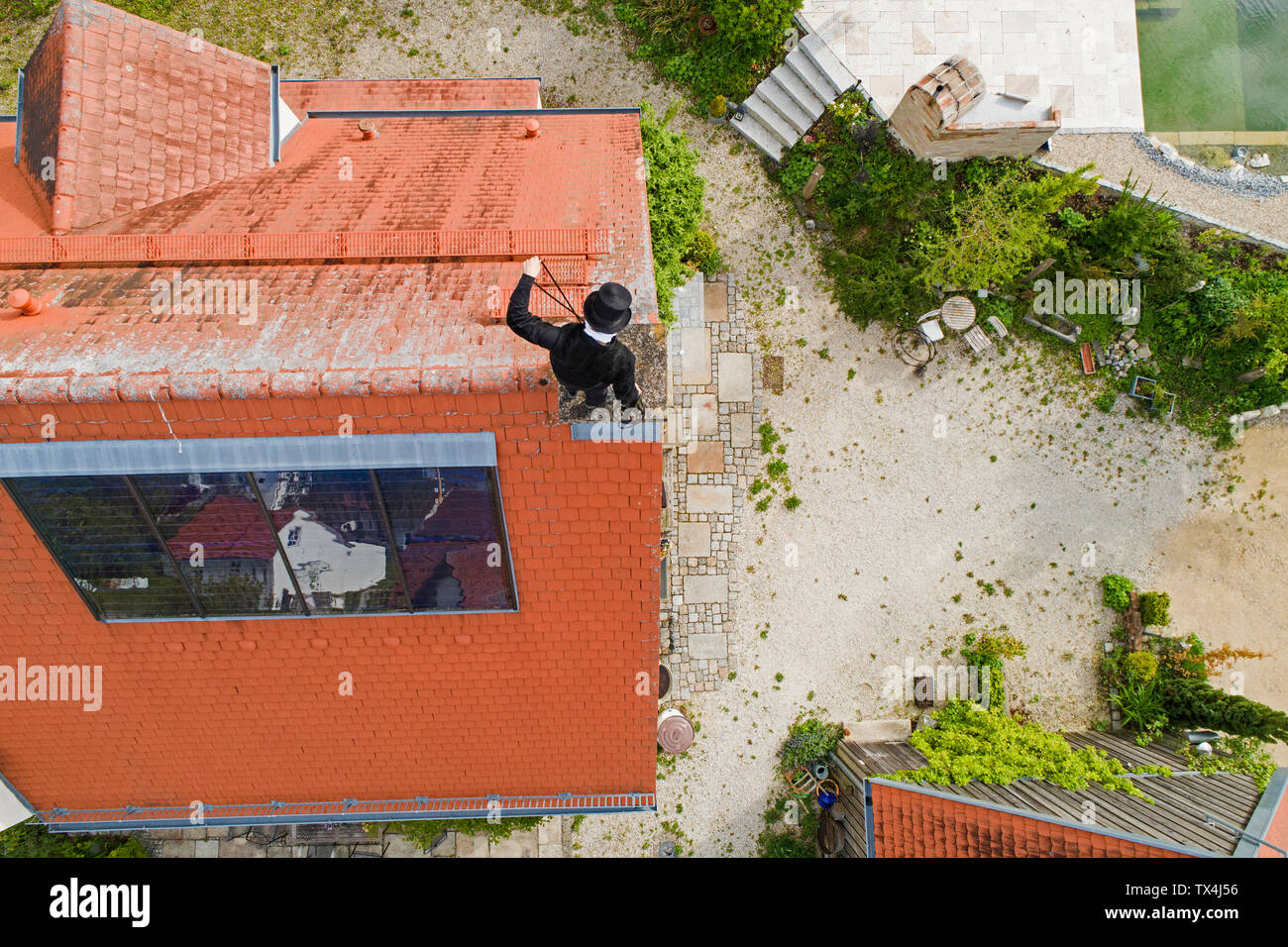 Aerial view of chimney sweep working on house roof Stock Photo