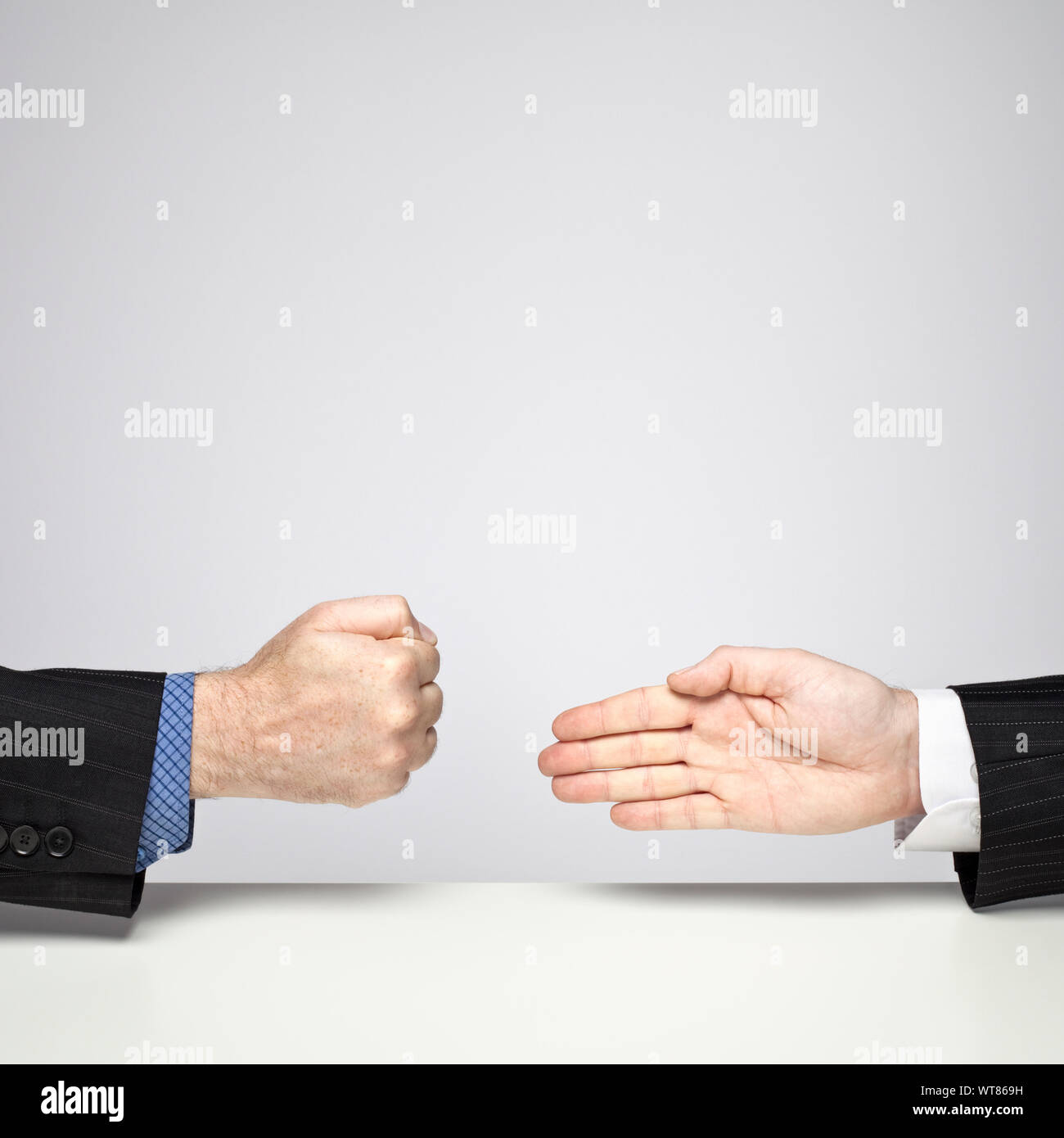 Two businessmen playing Rock, Paper, Scissors – Paper beats Rock Stock Photo