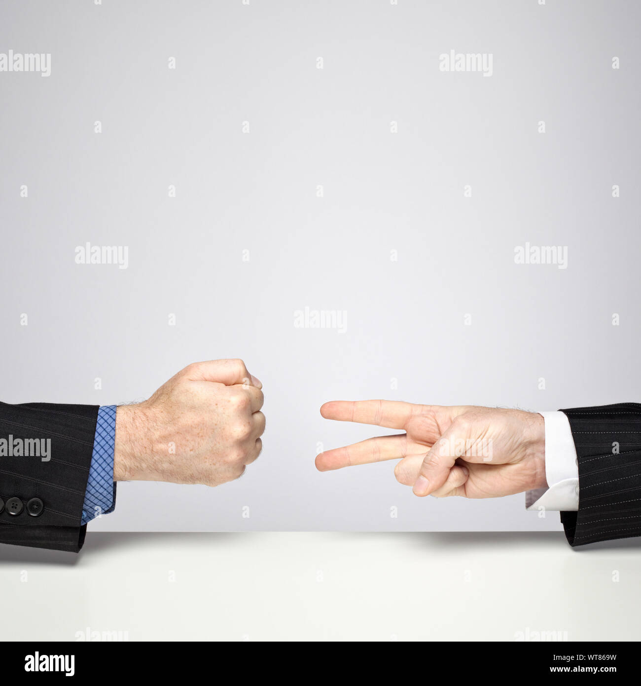 Two businessmen playing Rock, Paper, Scissors – Rock beats Scissors Stock Photo