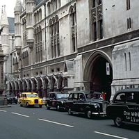 The Strand and the south facade of the Royal Courts of Justice, London. The griffin-topped Temple Bar, which marks the boundary between Westminster and the City of London, was erected in the 1670s to replace the 14th-century Temple Bar gatehouse.