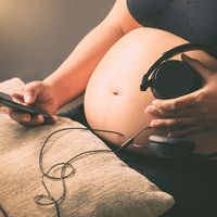 Pregnant woman holding headphones on her belly