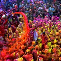 Hindu Holi Festival celebrations with colored water, powder and colorful flower petals thrown over celebrants at a Hindu temple in Mathura, Uttar Pradesh, India on March 24, 2021.