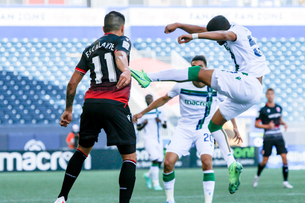 June 27, 2021. Cavalry FC vs. York United FC. First-Half. José Escalante watches as Terique Mohammed kicks the ball away.