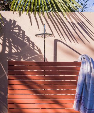 Outdoor shower painted pink with a wooden slatted privacy screen