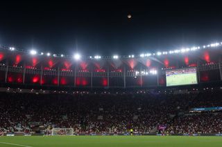 A tiny orange sphere above a curved football stadium