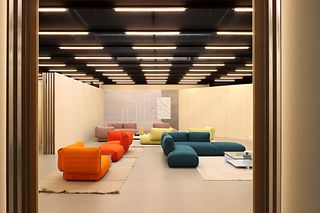 A open plan room with multi-coloured L shape sofas, rugs and tables.