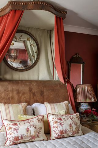 bedroom with red walls, red fabric canopy, leather bed