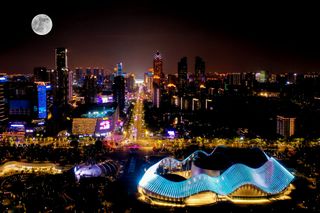 A silver sphere above a city lit with neon pinks, yellows, and blues