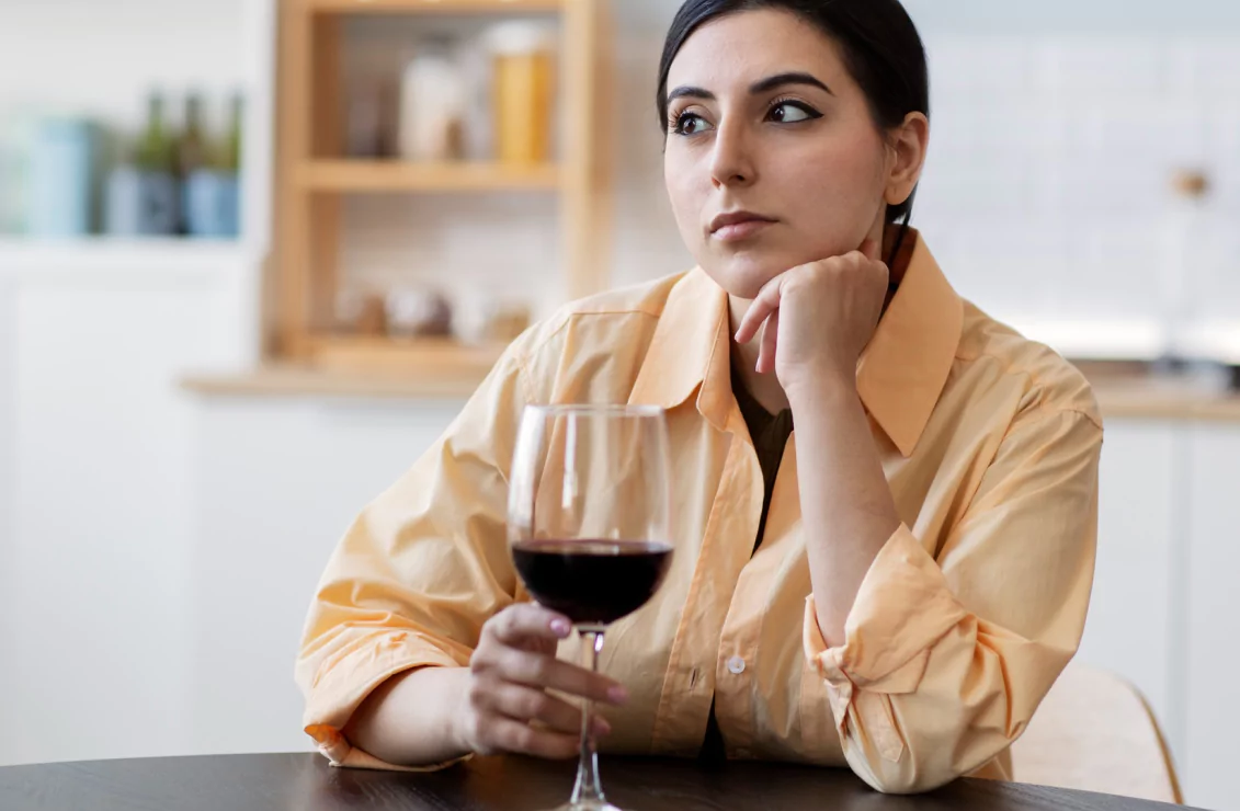 A woman at a table, savoring a glass of wine