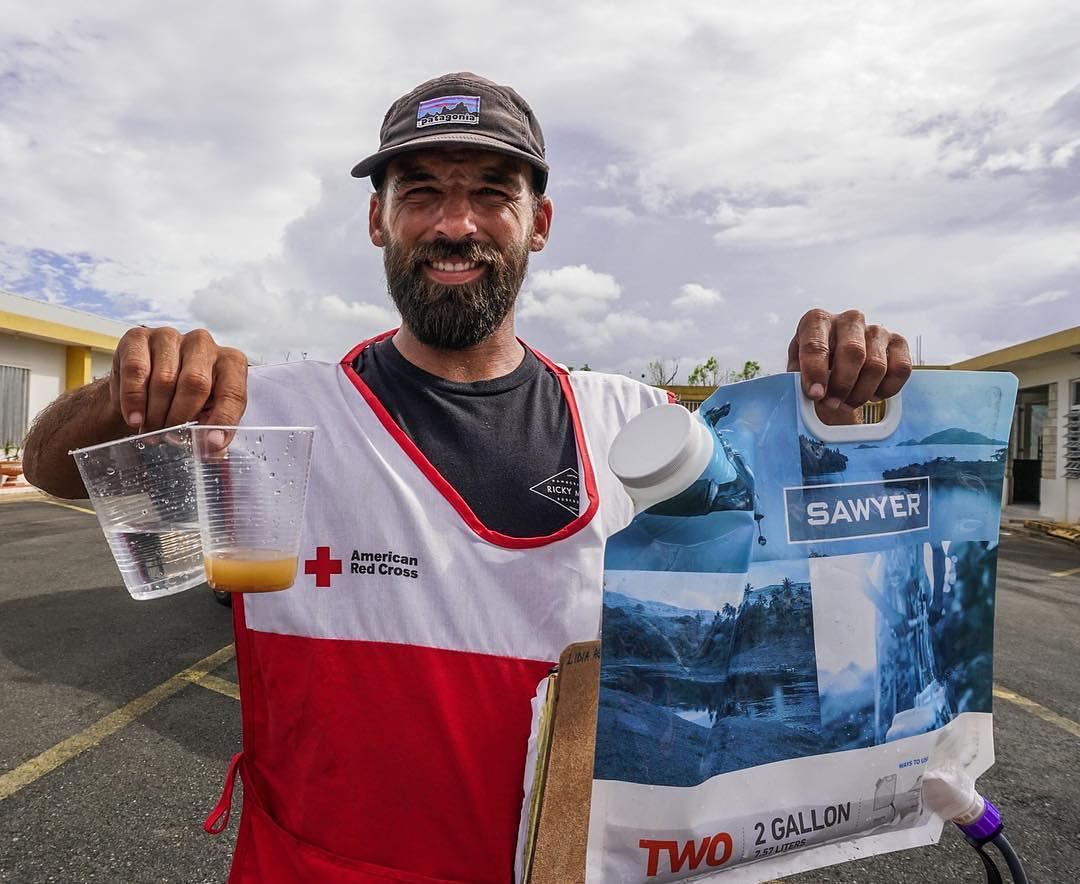 Man holding comparison dirty and clean water from two gallon filter bag