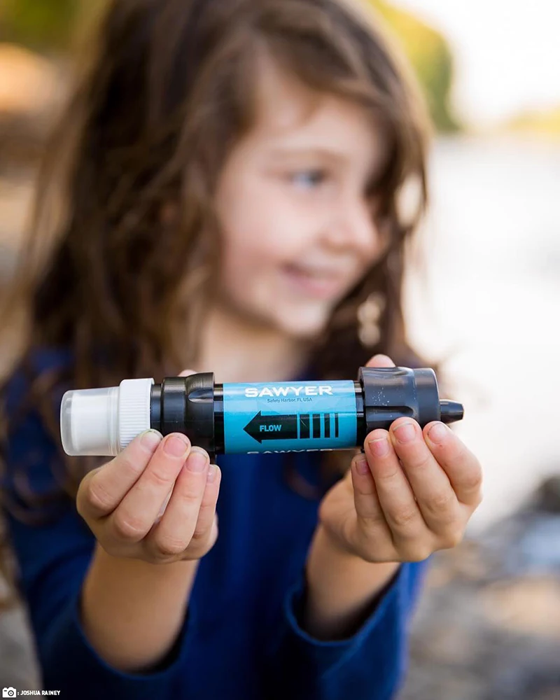 A girl holding a Sawyer dual threaded mini water filter