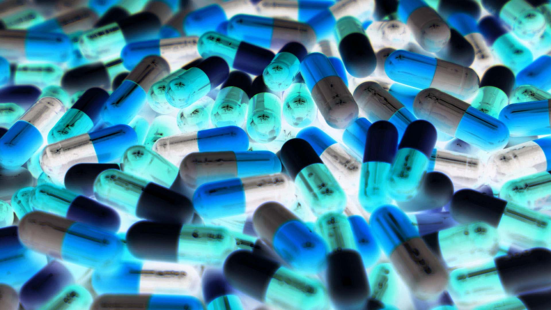 Pile of blue, green, and white color of capsule pills with modern design light.