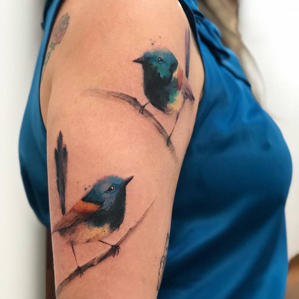 Watercolor blue wren birds on the upper arm.