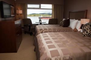 a hotel room with two beds and a flat screen tv at Inn on the Harbour in Prince Rupert