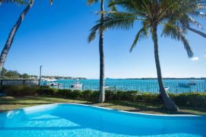 a swimming pool with palm trees and the water at Garden Villas in Grand-Baie