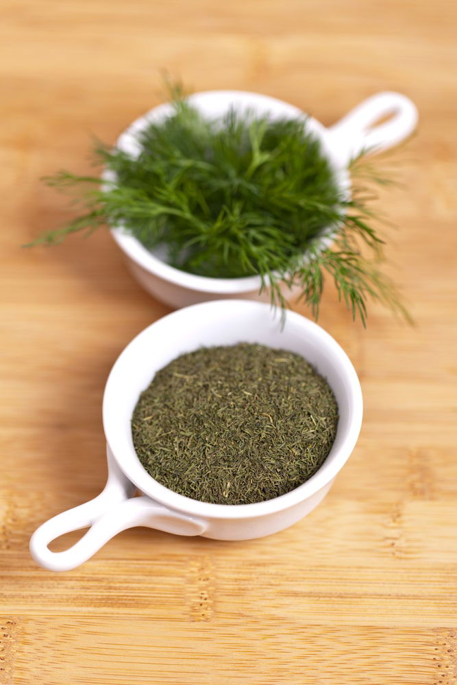 Turkish spices, including dill powder, are displayed in two bowls on a wooden table in Turkey.