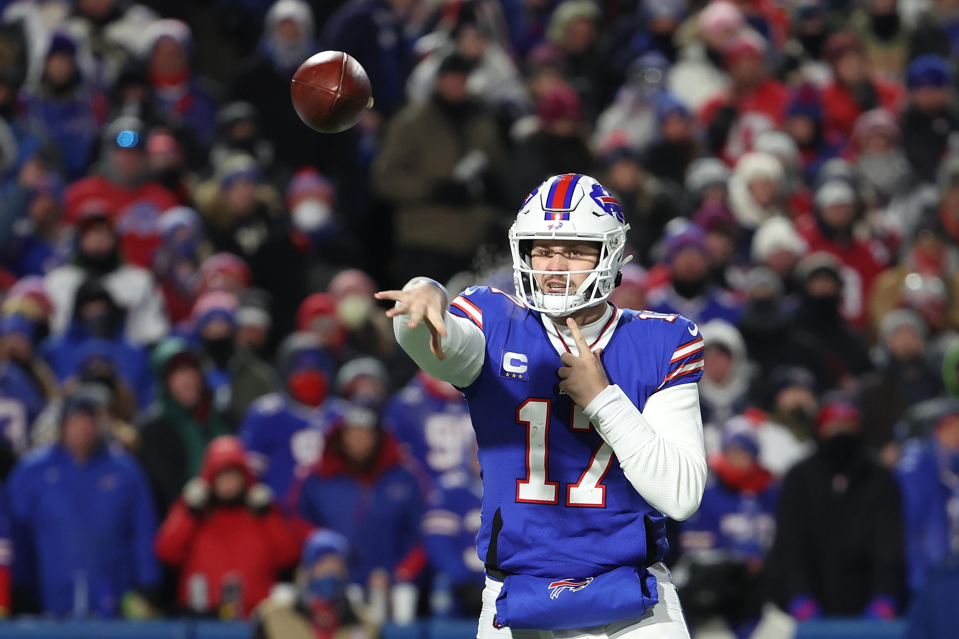 Allen following through on his pass as the ball spins through the air, fans in the stands behind him