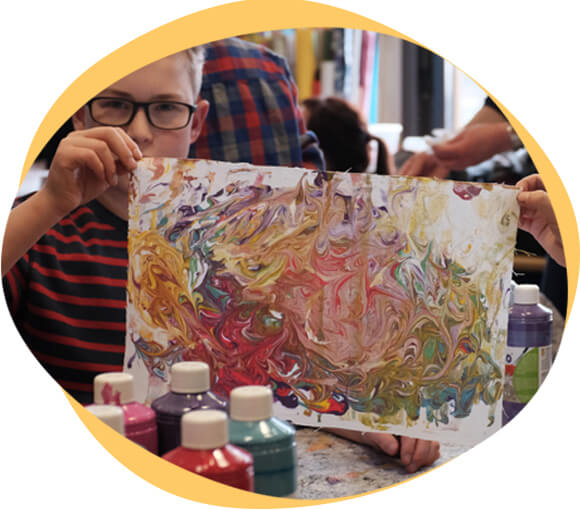 Young boy holding up his painting.