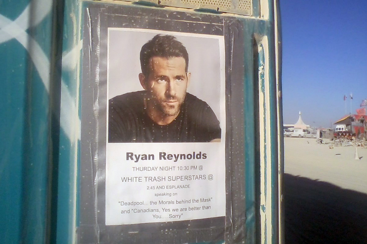 Burning Man 2019 poster reads: Ryan Reynolds, Thursday Night 10:30 PM @ WHITE TRASH SUPERSTARS @ 2:45 and Esplanade, speaking on “Deadpool... The Morals behind the Mask” and “Canadians, Yes we are better than you.... Sorry.”