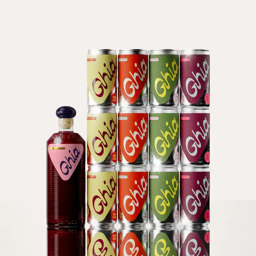 Glass bottle and stacked colorful Ghia beverage cans arranged in a grid pattern.